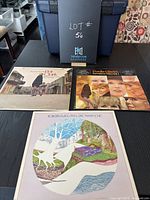 Photo showing three vinyl albums on a table with a blue storage bin and black backdrop labeled LOT #56.