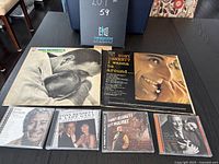 Top view of two Tony Bennett vinyl albums side by side with four Tony Bennett CDs below them on a black table.