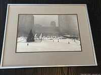 Framed black and white photograph showing Toronto City Hall skating rink and skaters with buildings in background.