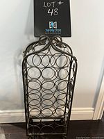 Front view of metal wine rack with heart-shaped handle and circular bottle holders.