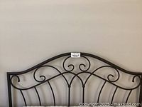 Front view of black iron queen size headboard showing scroll and line design.
