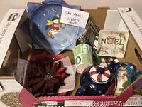 Overall view of Christmas themed kitchen ceramics in a box, showing plates, mugs, teapot, and decorative pieces.