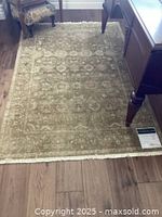 Full view of the sage colored Ethan Allen rug laid on wood floor, showing size and pattern