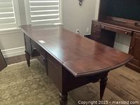 Front perspective of the Ethan Allen desk showing the cinnabar wood finish and the extended length with leaf extensions visible.