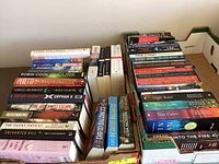 Photo showing a collection of 38 fiction books by various well-known authors packed in boxes, titles visible on spines.