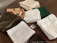 Multiple stacks of cloth napkins in solid colors and floral patterns seen on a brown surface.