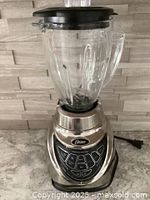 Full view of Oster Pro 500 blender showing glass jar on metallic stainless steel base with buttons visible.