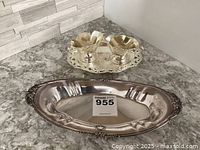Ornate Reed & Barton plated silver elongated oval bread plate with decorative edges and cream and sugar set with tray behind it