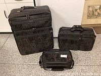 Three Samsonite soft luggage pieces on floor; large suitcase, medium briefcase, and small carry bag in black paisley fabric.