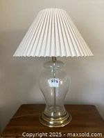 Photo of one glass table lamp with white pleated fabric shade and antique brass base, unlit