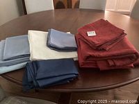 Various folded cloth pieces in red, navy blue, light blue, and white on a round wooden table