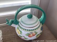 Close-up of Villeroy & Boch metal teapot with teal handle and fruit pattern