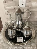 Four piece tea set on black enamel tray including teapot, creamer, sugar bowl with lid.