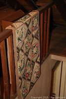 Vintage looped floral geometric patterned rug draped over wooden railing