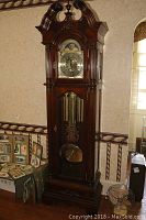 Full front view of mahogany grandfather clock showing entire case, base and pediment