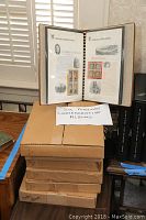 Six American commemorative stamp albums stacked, with one open showing detailed information pages and stamps. Albums stored in original boxed packaging.