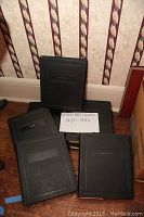 Seven black cover albums stacked with visible label 'Cover Album' in black faux leather style covers. A handwritten sign reads 'First Day Covers 1937-1952'