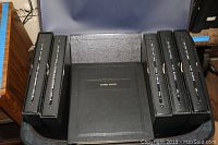 Six black cover albums labeled 'Cover Album' arranged sitting upright inside a blue Pullman suitcase.