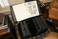 Open Pullman suitcase showing six black three-ring binders filled with stamp album pages