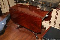 Closed drop leaf table with rich wood grain and claw feet base, minimal wear visible