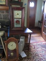 Group view showing rectangular wood-cased clock, Howard Miller pendulum wall clock, and small mantel clock