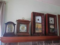 Group of four wood-cased mantel and wall-hang clocks on mantel