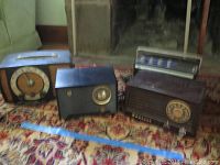 Four vintage radios arranged on carpet including RCA Victor, Admiral, Zenith and a mini boom box by Lear Jet.
