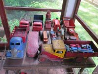 Overhead view of assortment of pressed steel toy trucks and vehicles on a wooden shelf