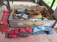 Box of assorted metal toy vehicles including tracked tractor body, dump trucks, bus station and gas pump