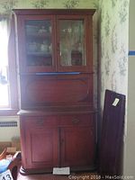 Full frontal view of the secretary desk showing upper glass cabinet, drop-front desk section, locking drawer, and lower cabinet.