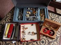 Overview showing jewelry in blue holder, red box with tie pins, and wooden box with cuff links along with 5 utility knives.