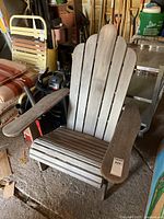 Full view of the wooden Adirondack chair showing the weathered wood slats and overall wear.