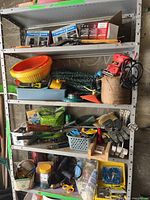 Full view of metal shelving unit with assorted tools and garden supplies including sawhorse brackets, trowels, garden hose, palm sander, colander, gloves and bottles