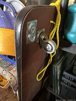 Close-up image showing caster wheel mounted on underside of wooden board and yellow rope tied through holes.