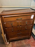 Front view of solid wood dresser with four drawers and metal handles, showing overall condition and style.