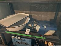 Enamel tray and basin stacked on a shelf with two tape measures nearby