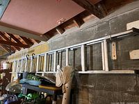 Side view of aluminum extension ladder hung on wall with other items below