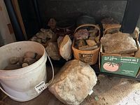 Wide view of large Rose Quartz and smaller rocks in boxes and bucket.