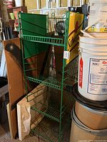 Full angled view of green metal Schweppes soda display rack, showing three wire shelves and Schweppes logo on side panel.