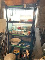 Resin shelving unit filled with various items like containers of paint or chemicals, metal rods, and other miscellaneous garage items. Photo shows shelving unit in a workshop or garage environment.