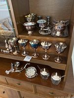 Full view of silver plated dining and decorative items including wine glasses, sugar and cream sets, and salt and pepper shakers