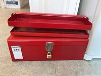 Front view of the open red metal tool box showing two removable trays and the main compartment beneath.