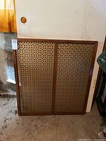 Front view of the vintage wooden screen with two ornately carved panels and a natural wood frame showing signs of wear