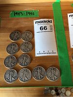 Overhead view of ten Walking Liberty half dollars arranged on wood surface with date range label.