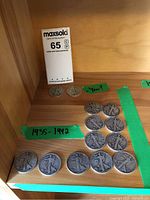 Overview of 13 Walking Liberty half dollars arranged on shelf with green tape marking date range