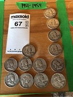 Wooden surface with thirteen Franklin half dollars and auction card, obverse views