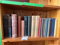 Full shelf view showing all 16 hardcover books lined up, showing titles and general condition.