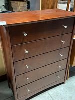 Full view of five-drawer chest with dark cherry finish and silver knobs