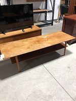 Front angle view of rectangular teak table showing top surface and lower shelf