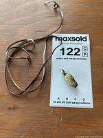 Pendant and leather necklace laid on wooden surface next to auction lot card